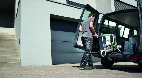 Un artisan charge son atelier mobile Festool dans son véhicule, prêt à intervenir sur un nouveau chantier.