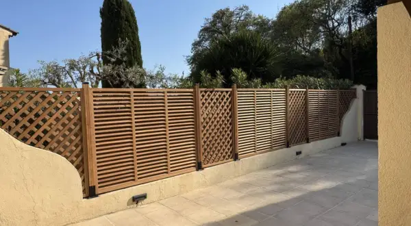 Une belle clôture en bois, parfaite pour un entretien facile et un style moderne. Elle délimite un espace extérieur avec des arbres en arrière-plan.