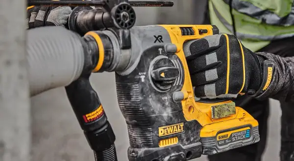 Main d'un ouvrier tenant un marteau-piqueur DeWalt origine, prêt à travailler sur un chantier.