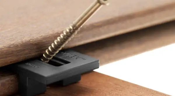 Démonstration de comment visser lame terrasse bois avec un clip invisible. La vis traverse le clip pour fixer la lame.