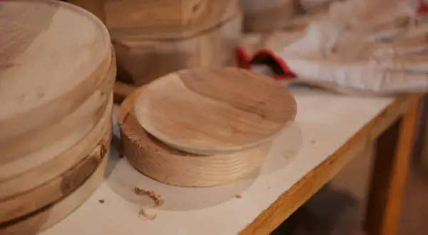 Assiette en bois brut sur un tour, avec des copeaux. Une belle idée de tournage sur bois pour créer des objets uniques.