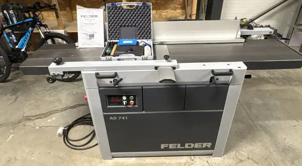 Rabot dégau Felder AD 741, prêt à l'emploi dans un atelier. Un vélo est garé à proximité.