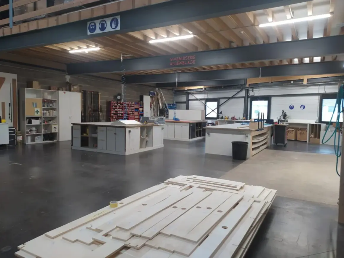 Un atelier de menuiserie bien organisé, avec des établis, des étagères et des matériaux prêts pour de nouvelles créations. Une belle idee amenagement atelier.