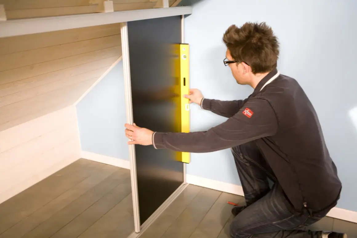 Un homme utilise un niveau pour fabriquer un placard sous pente de toit.