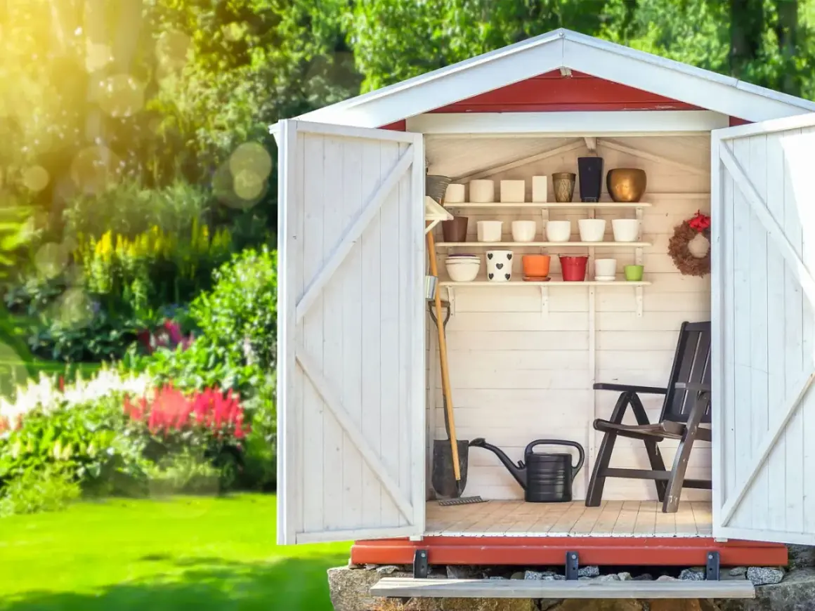 Aménagement abri de jardin : outils, pots de fleurs et chaise attendent le jardinier.