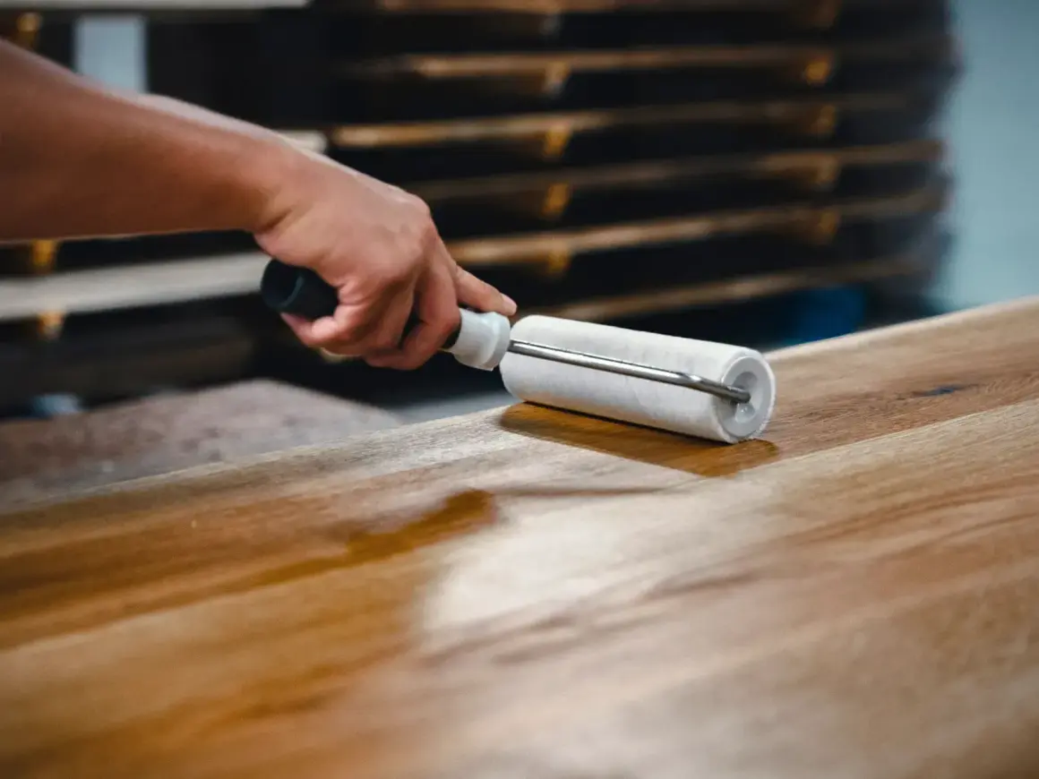 Application d'un vernis ou vitrificateur sur un plateau en bois avec un rouleau pour le protéger et le faire briller.
