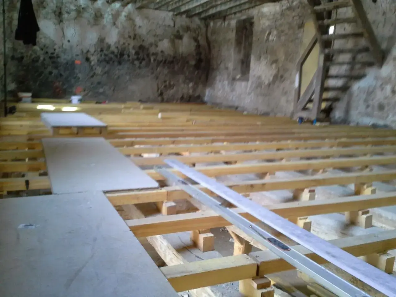 Pose de plancher OSB sur solives en bois dans une pi&egrave;ce en r&eacute;novation. Des panneaux sont d&eacute;j&agrave; pos&eacute;s.