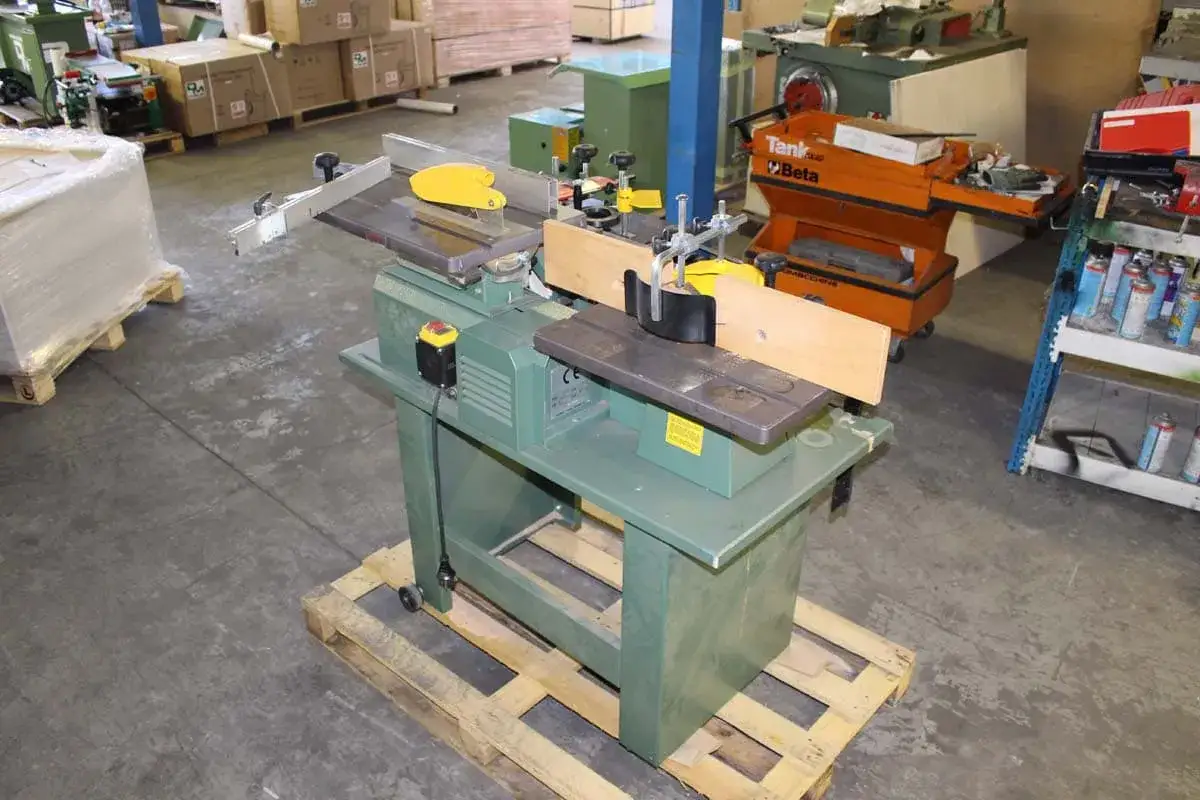 Machine à bois verte, une scie kity, avec des outils et des boîtes en arrière-plan.