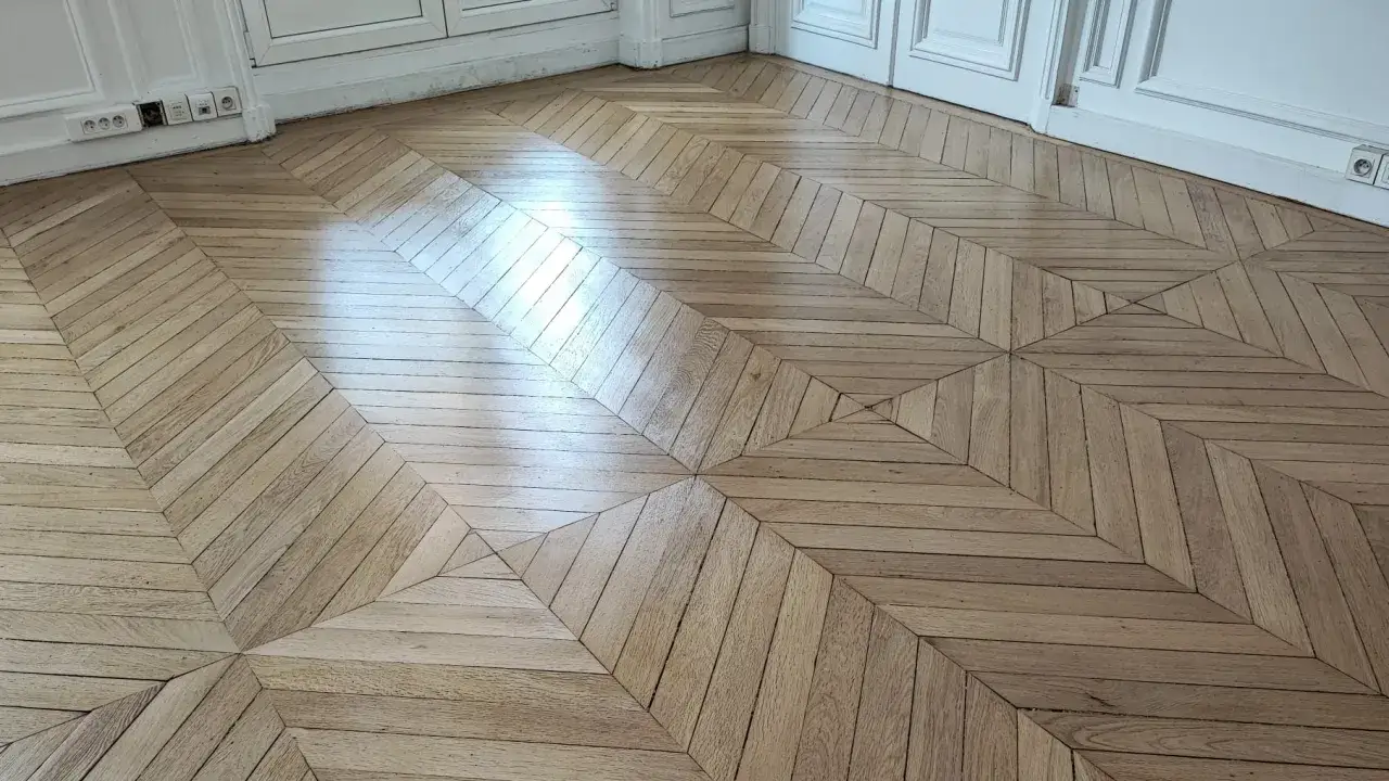 Parquet en bois clair avec un motif géométrique complexe, prêt pour le ponçage.