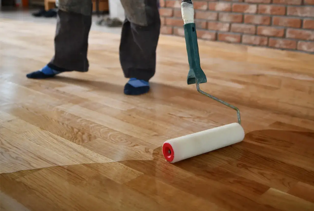 Application d'un vitrificateur sur un parquet en bois. Le temps de s&eacute;chage est crucial pour un r&eacute;sultat impeccable.