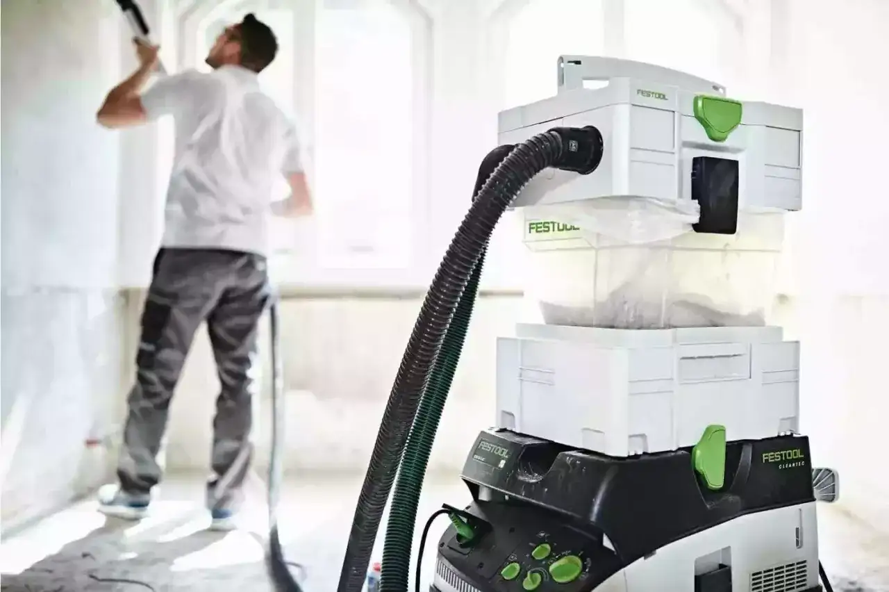 Un artisan utilise un aspirateur Festool CT VA 20 pour un chantier propre.