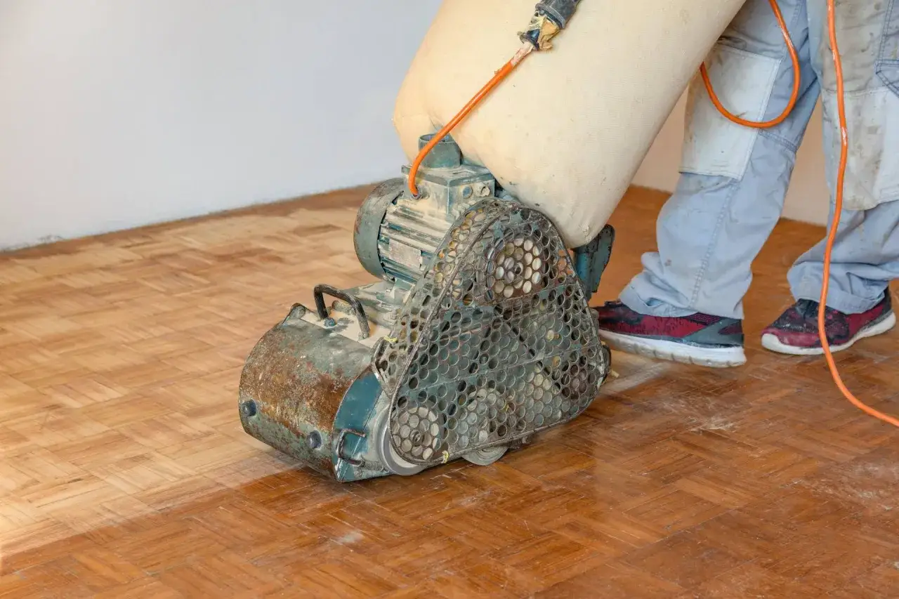 Machine &agrave; poncer le parquet en action. Le sac de poussi&egrave;re est plein, indiquant un long temps de s&eacute;chage du fond dur.