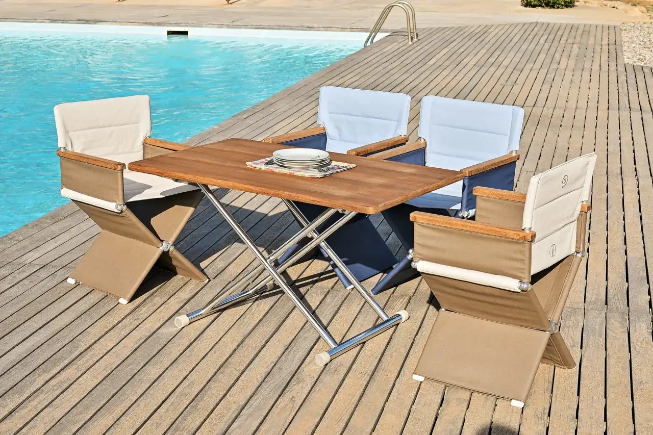 Table et chaises pliantes en bois teck, installées sur une terrasse en bois, près d'une piscine.