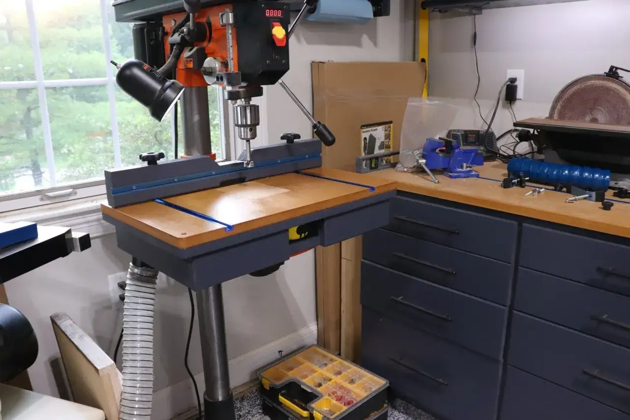 Un &eacute;tabli de menuiserie avec une perceuse &agrave; colonne et un support fait maison pour la stabiliser.