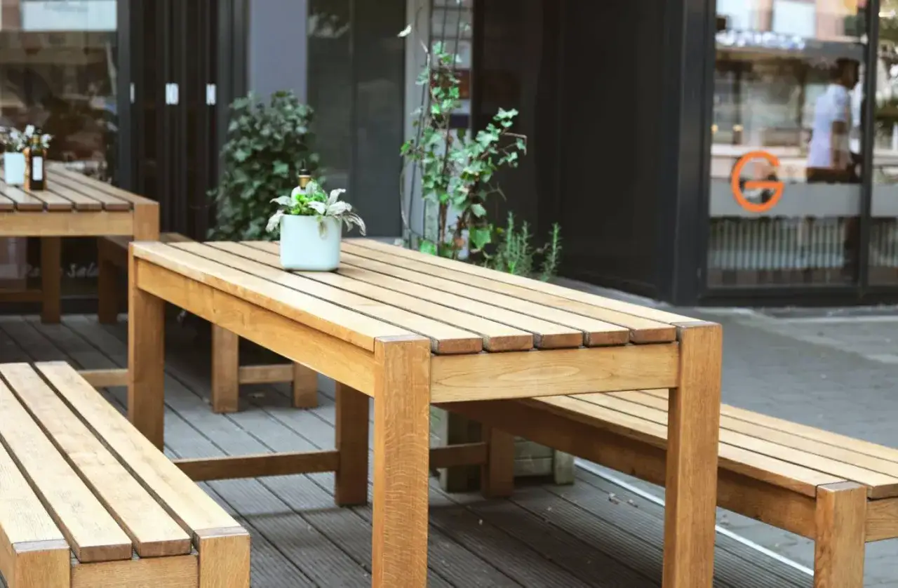 Une table en bois et ses bancs sont install&eacute;s sur une terrasse. Parfait pour savoir si on peut mettre une table en bois dehors.