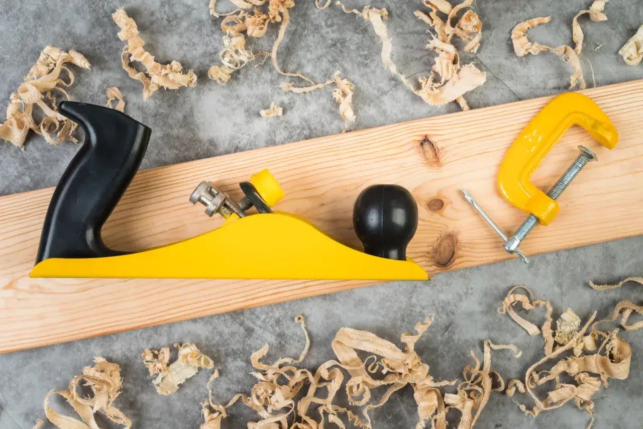 Outil de menuiserie jaune et noir sur une planche de bois, entouré de copeaux de bois. L'egrenage est prêt pour le travail.