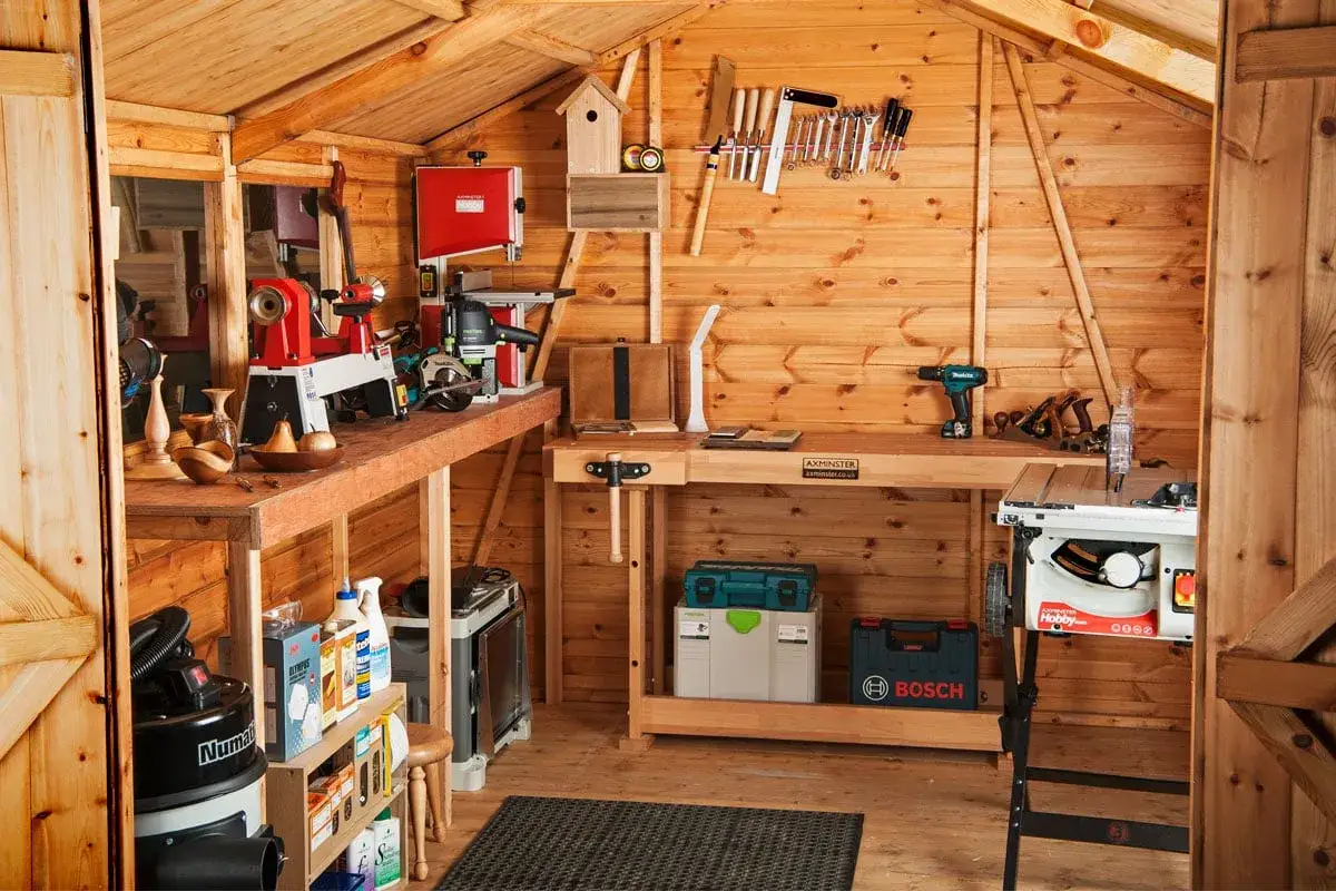 Atelier de menuiserie bien &eacute;quip&eacute; avec tour &agrave; bois, scie &agrave; ruban, perceuse et divers outils &agrave; main.