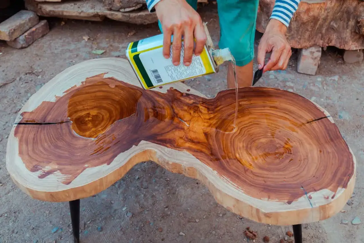 Application d'essence de t&eacute;r&eacute;benthine sur une table en bois brut pour en r&eacute;v&eacute;ler la beaut&eacute; naturelle.