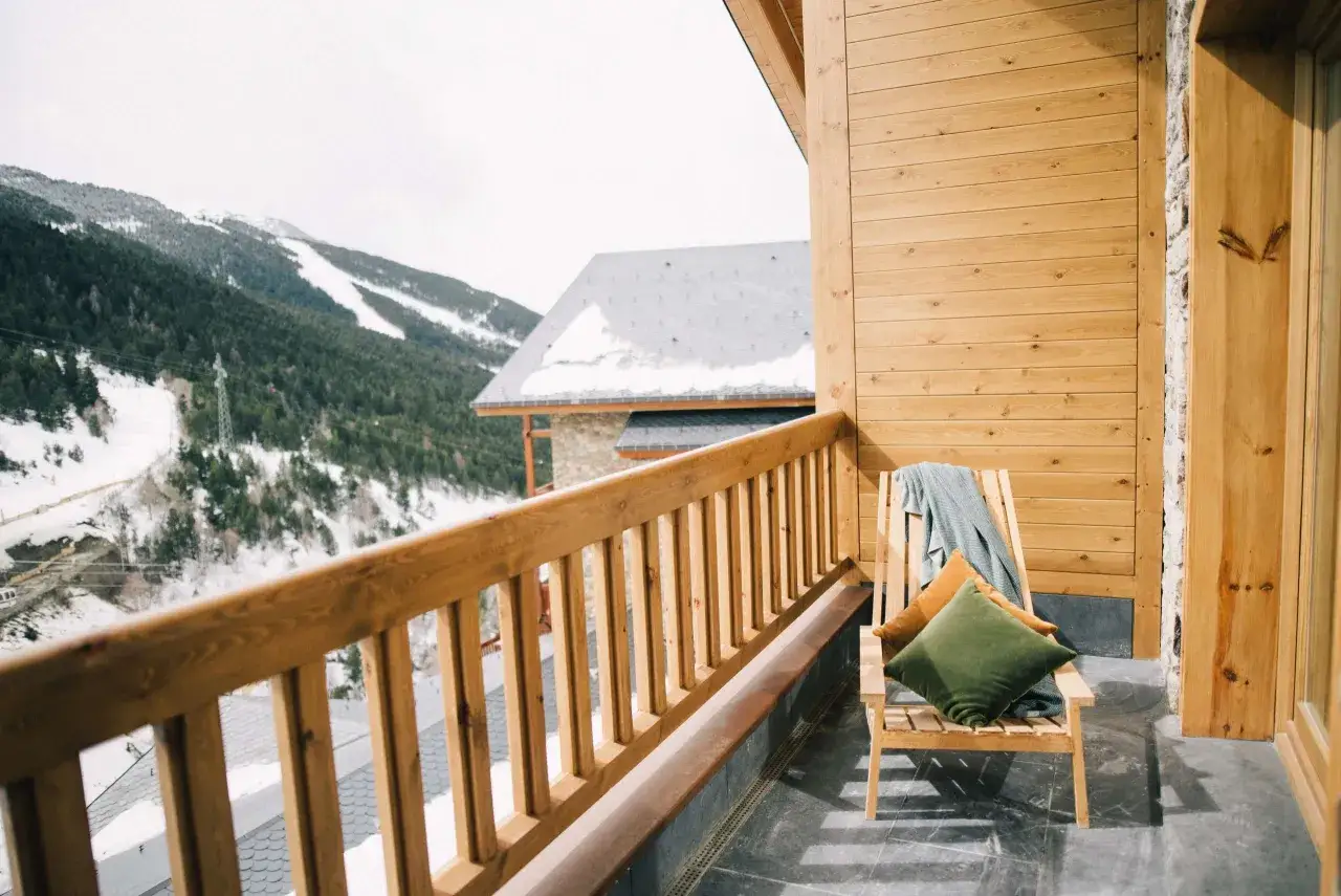 Balcon en bois d'un chalet, vue sur les montagnes enneig&eacute;es. Id&eacute;al pour l'entretien chalet bois et la d&eacute;tente.