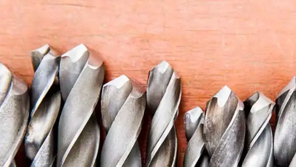 Ensemble de forets métalliques sur fond de bois. Apprenez comment mettre un foret dans une perceuse pour vos projets.