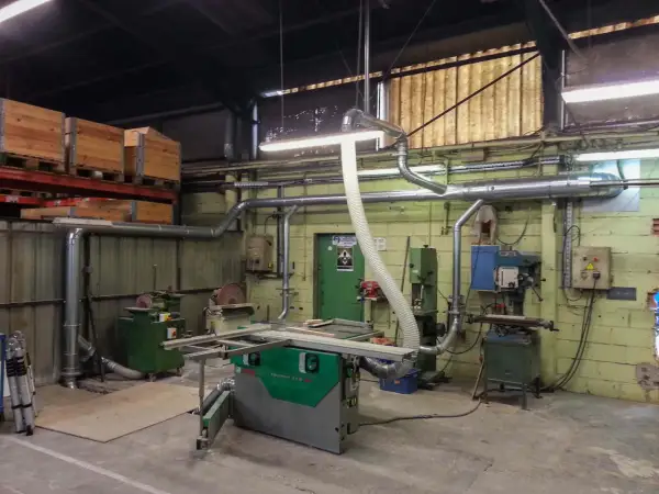 Atelier de menuiserie avec scie, dégauchisseuse, et une aspiration atelier bois occasion pour un environnement de travail propre.