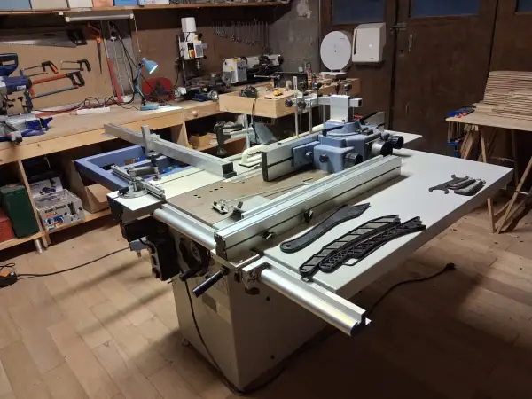 Un atelier de menuiserie avec une machine combinée Felder KF 500, des outils et des planches de bois.