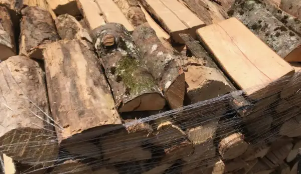 Bois empilé, prêt à sécher du bois rapidement. Des bûches de différentes tailles, certaines avec de la mousse, sont emballées dans du film plastique.