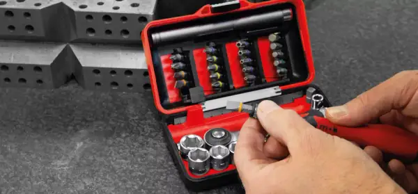 Une main insère un embout dans un cliquet rouge. Ce coffret d'embouts et douilles est un exemple de marque outillage français, conçu pour la précision.