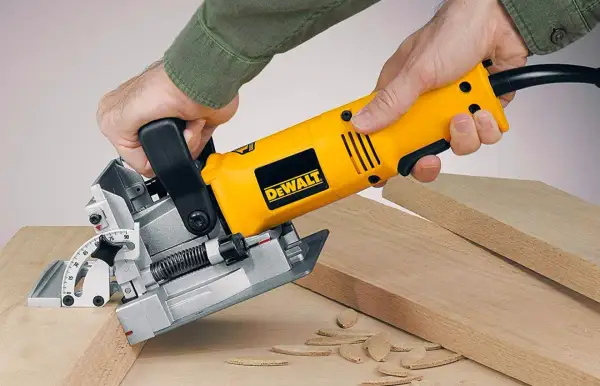 Main jaune DeWalt, une lamelleuse, utilisée pour assembler des planches de bois.