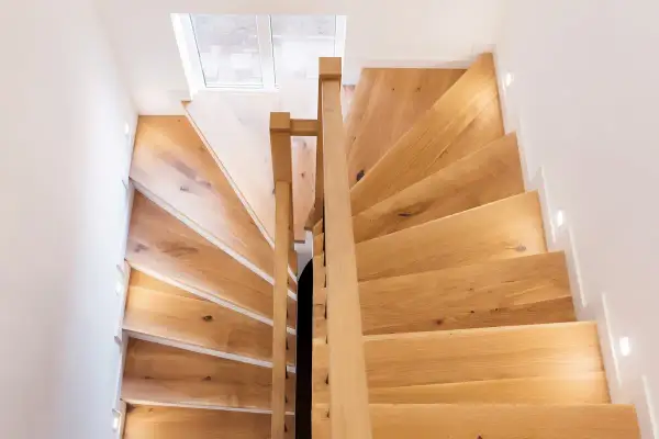 Escalier en bois clair, idéal pour un entretien facile à l'huile de lin. Lumières intégrées pour un éclairage doux.