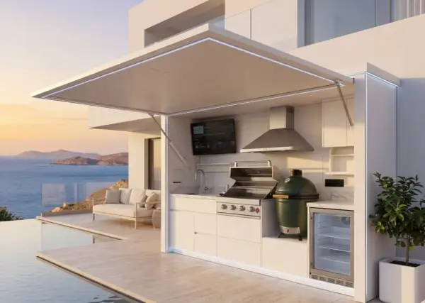 Une cuisine d'été fait maison moderne avec barbecue, évier, frigo et TV, surplombant la mer et une piscine.