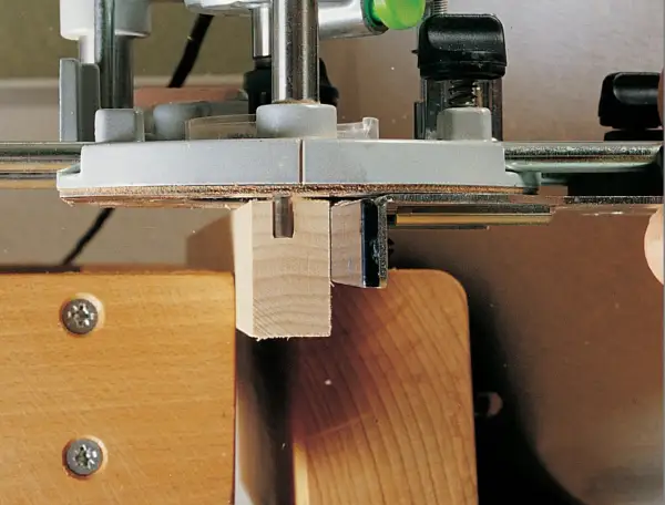 Utilisation d'un gabarit rainure défonceuse pour créer une entaille précise dans une pièce de bois.