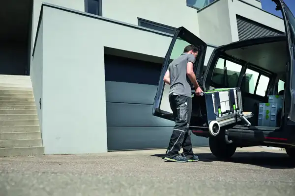 Un artisan charge son atelier mobile Festool dans son véhicule, prêt à intervenir sur un nouveau chantier.