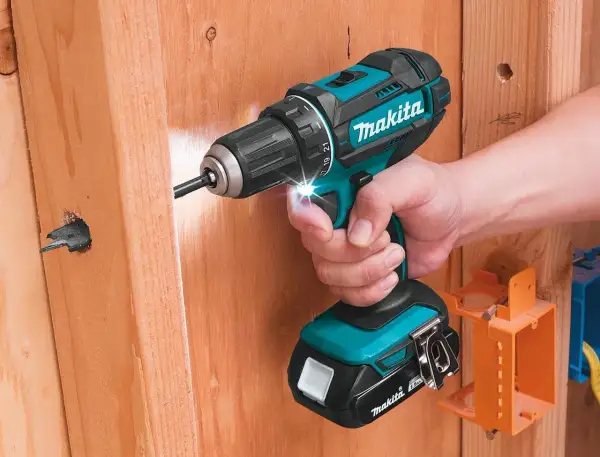 Comment reconnaître Makita Pro : une perceuse sans fil turquoise et noire de Makita est utilisée pour visser dans du bois.