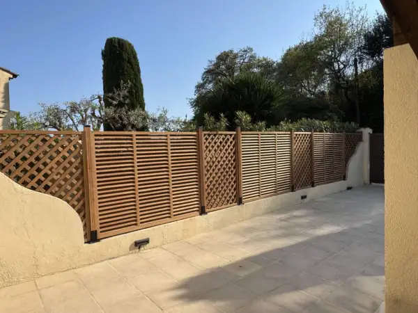 Une belle clôture en bois, parfaite pour un entretien facile et un style moderne. Elle délimite un espace extérieur avec des arbres en arrière-plan.