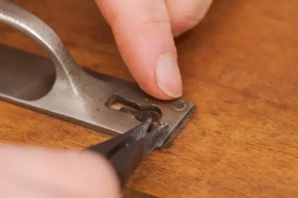 Maintenant, vous savez comment enlever une vis foirée. Une pince à épiler retire un morceau de vis endommagé d'une poignée de porte.