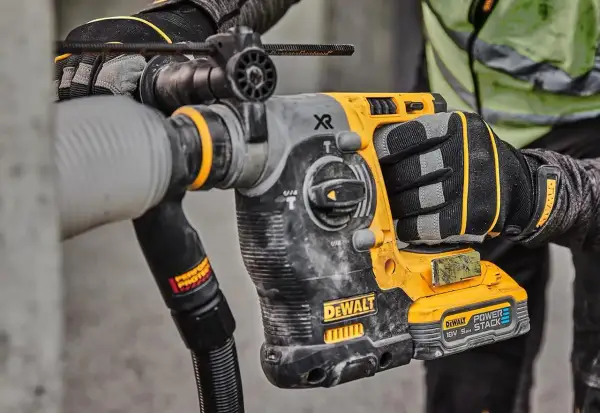 Main d'un ouvrier tenant un marteau-piqueur DeWalt origine, prêt à travailler sur un chantier.