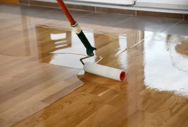 Application d'un vitrificateur sur un parquet en bois, lui donnant un aspect brillant et protecteur.